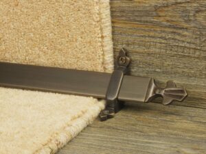 Louis design of stair rod with fleur-de-lys end, bronze on cream carpet