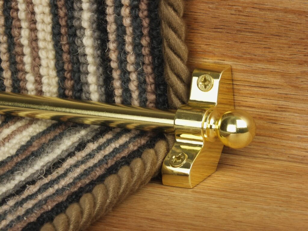 Jubilee stair rod in polished brass on striped carpet