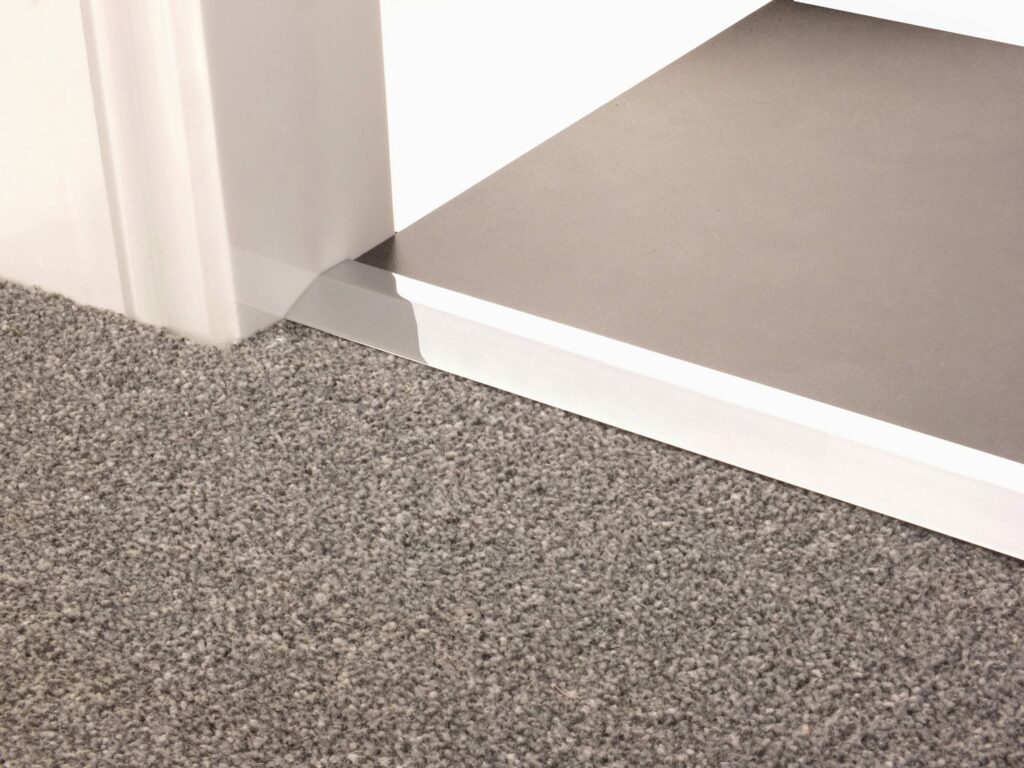 Carpet ramp joins different levels of flooring, carpet to tiles, chrome