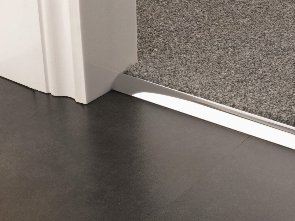 Carpet to vinyl  chrome door bar joining beige carpet to wood-look vinyl