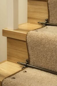 Stair rods and Easystuds installed on staircase, close-up of two steps in beige carpet