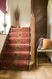 Homepride stair rods fitted on red patterned runner up wooden stairs