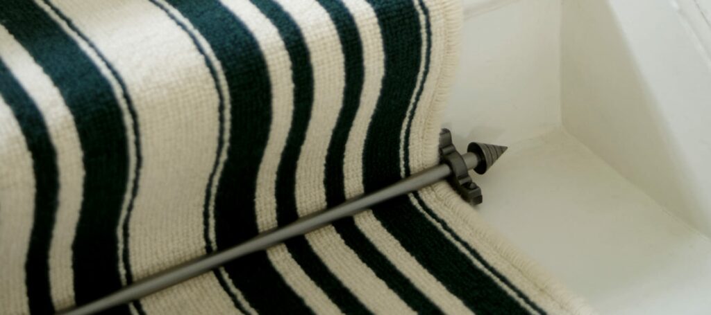Arrow carpet rod with bracket in black fitted to striped stair runner