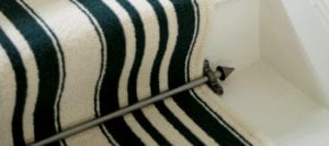 Arrow carpet rod with bracket in black fitted to striped stair runner