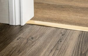 Satin brass Premier Z4 door threshold strip joining a thin flatweave carpet to a wood floor