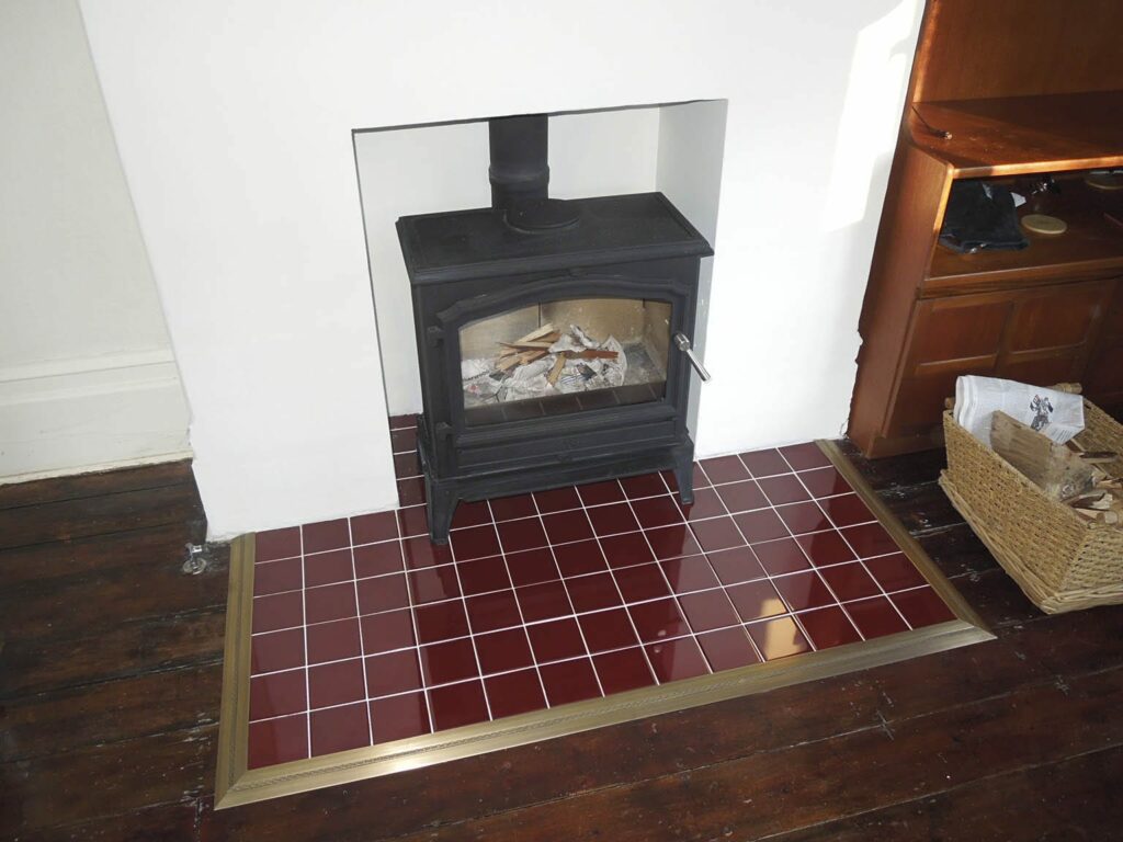 Fire hearth edging in antique brass around red tile hearth