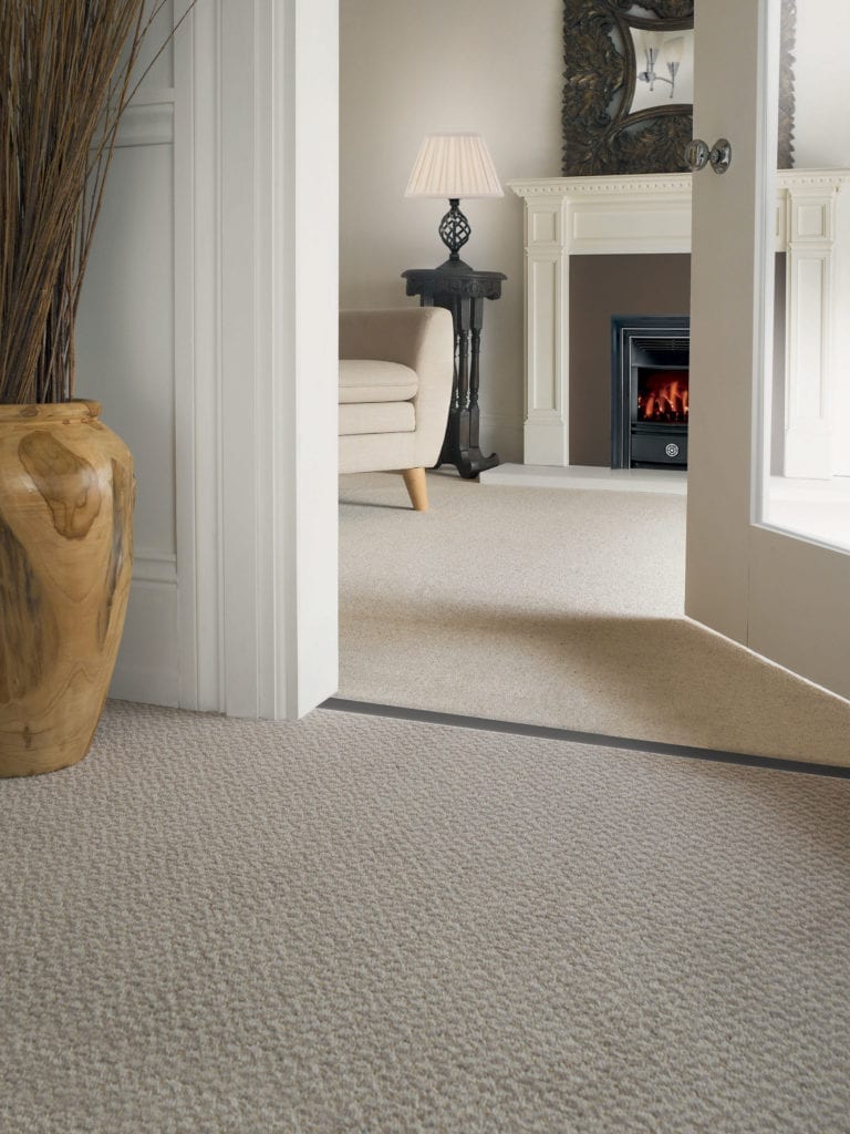 Carpet door strip joins beige carpets from hall to living room with fireplace