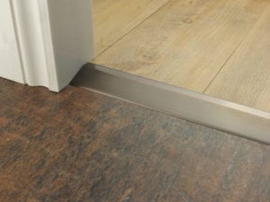 Button for door bar ramp that transitions from one floor level to another, bronze