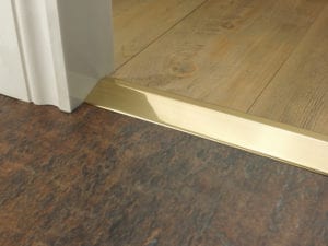 Door bar ramp that transitions from one floor level to another in polished brass