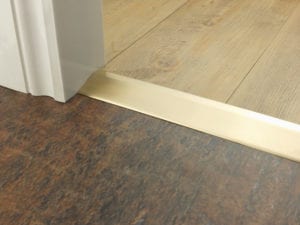 Door ramp in satin brass finish that transitions from one floor level to another