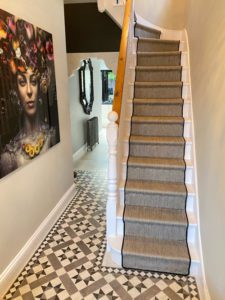 Black rope carpet binding on natural stair runner with encaustic tile hall floor