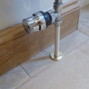 Speher pipe collar fitted around bottom of radiator pipe on tiled floor