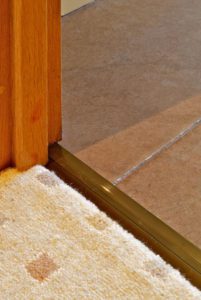 Posh door thresholds joining brown tiles to patterned carpet