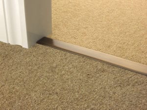 Carpet door thresholds joining beige carpets in antique brass