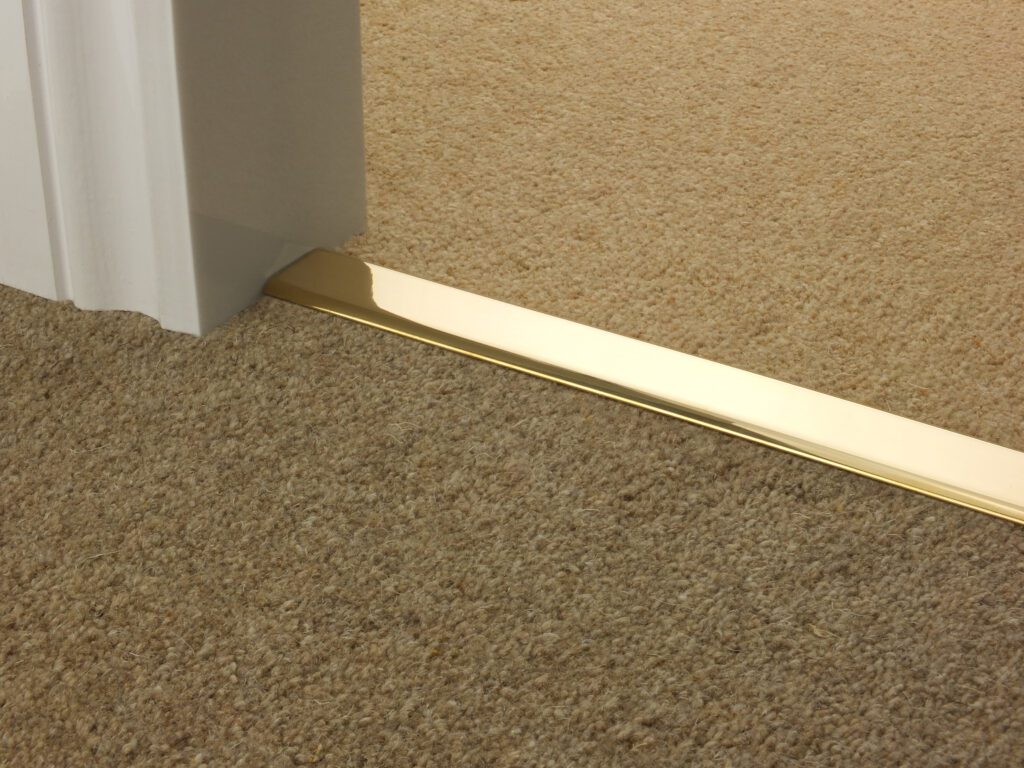 Carpet threshold strips, polished solid brass joining two brown carpets