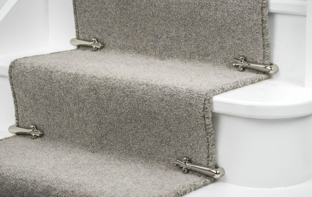 fleur-de-lys design stair carpet clips on a beige stair runner